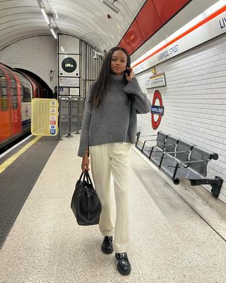 @symphonyofsilk wearing white trousers, grey jumper and loafers