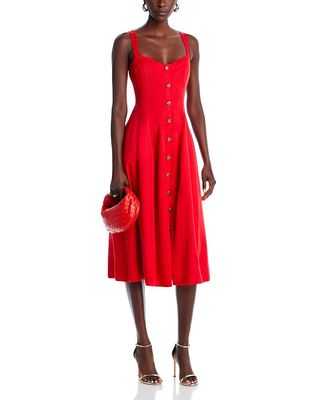 Red Aqua x Liat Baruch dress with gold buttons shown on a dark skinned model with gold stiletto heels and a red woven bag.