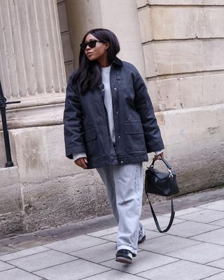 @_loissterling wears a navy canvas jacket with grey jeans and black trainers