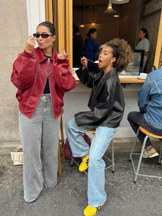 @amaka.hamelijnck and @bentheliem outside a cafe weating on-trend leather jackets and jeans.