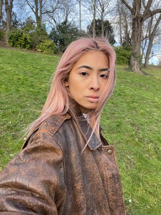 Fashion influencer @himichelleli with pink hair wearing a distressed brown leather jacket.