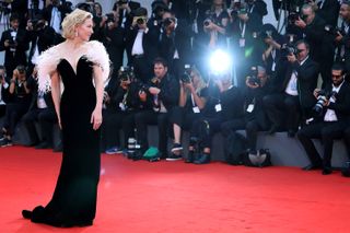 Cate Blanchett looks over her shoulder on the red carpet at the Venice Film Festival wearing a black gown