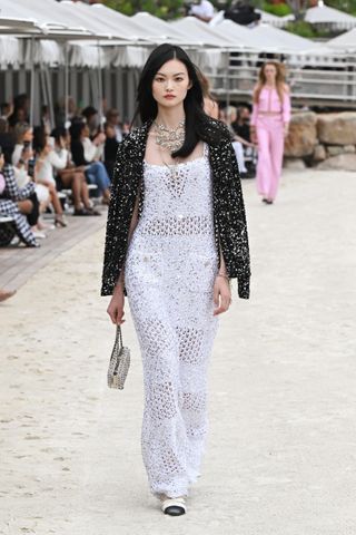 a model walks the Chanel runway wearing a white crochet gown