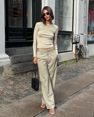 French woman wearing a fitted top and low-rise trousers.