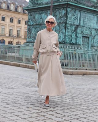 Woman wearing a tan A-line skirt with a matching jacket.