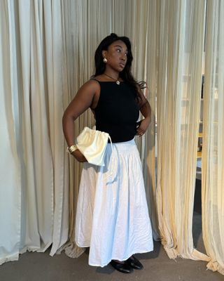 Nnennae Chem in a black tank top and white midi skirt.