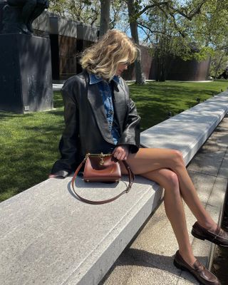 Elsa Hosk wearing a leather jacket, denim shirt, and loafers