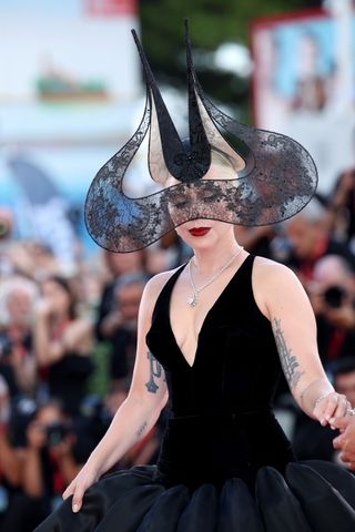 Lady Gaga wears a black lace headpiece by Philip Treacy at the Joker premiere