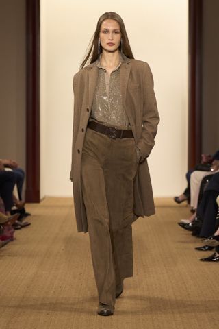 A Ralph Lauren F/W 24 look including a tan suede long jacket with matching belted trousers and a button-down shirt.