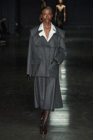 An Emilia Wickstead look from the F/W 24 collection including a white button-down shirt worn under a gray wool jacket with a matching A-line skirt.