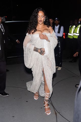 Rihanna wears an off-the-shoulder silver dress with strappy high heels