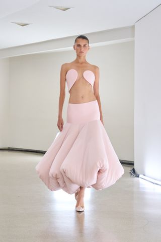 a model wears a pink cutout dress with a voluminous midi skirt