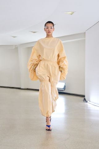 a model wears a light yellow jumpsuit on the runway at Alaïa