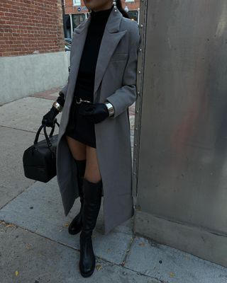 @dawn.tan wearing a black mini dress, boots and coat