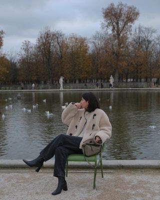 Woman wears textured buckle coat, black jeans and heeled boots