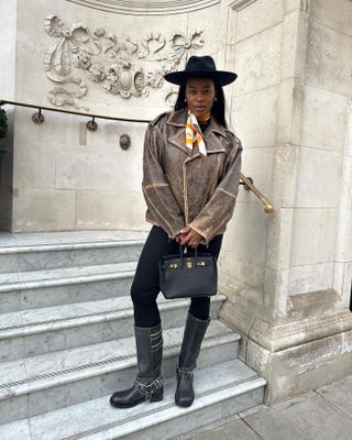 Woman wears leather jacket, leggings, biker boots, hat