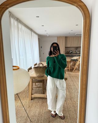 Monikh in a green jumper and white trousers