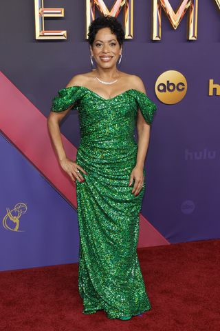 Liza wears a custom green off-the-shoulder sequin gown by Christian Cowan