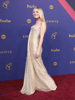 Dakota Fanning wears a champagne dress on the 2024 Emmys red carpet.