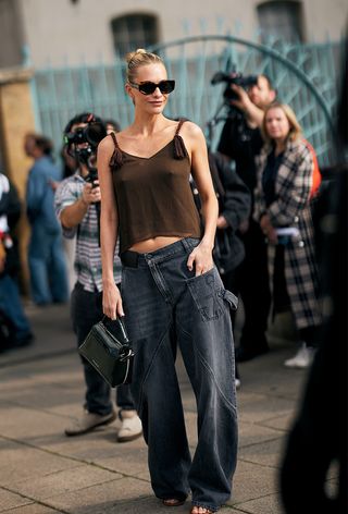 a street-style photo of Poppy Delevingne wearing a brown tank top and black jeans for JW Anderson's spring 2025 show