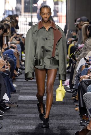 a model on the JW Anderson spring 2025 runway wearing moto boots with an oversized satin jacket