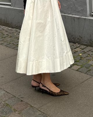 Woman wearing a white midi skirt and leopard print kitten heels