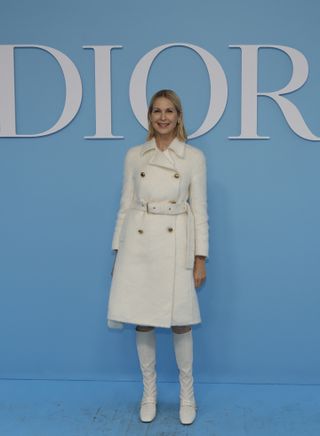 Kelly Rutherford wears a white belted trench with white knee-high boots.