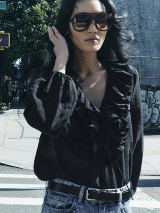 Zara model wearing a black ruffled blouse.