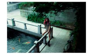 Model and actress Hoyeon stands next to a coy pond wearing a Stella McCartney dress.