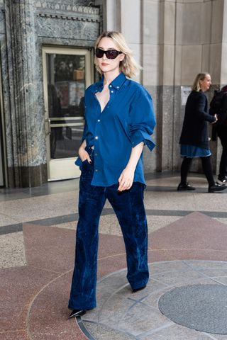 Saoirse Ronan is seen in Madison Square Park on October 01, 2024 in New York City wearing a navy blue shirt and matching corduroy pants by Ferragamo.