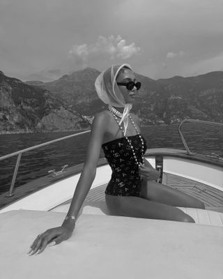 Dana Emmanuelle-Jean Ozime pairs a Chanel swimsuit with strands of pearls and a hair scarf