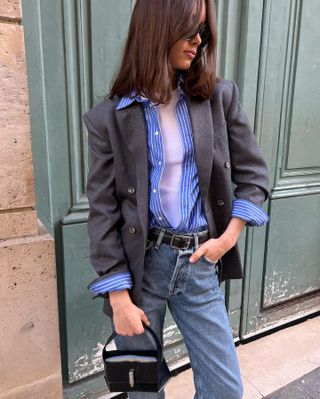 woman wearing a grey blazer, blue stripe shirt, and jeans