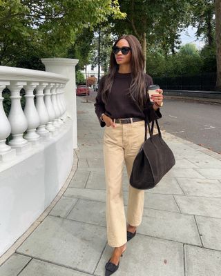 Woman wears a brown jumper, beige jeans, brown bag, brown shoes