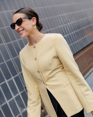 Woman in butter yellow jacket and glasses.