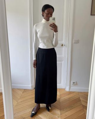 Sylvie Mus wearing a white turtleneck and black skirt