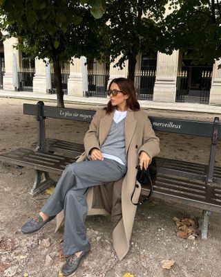 Woman in gray outfit and beige coat.