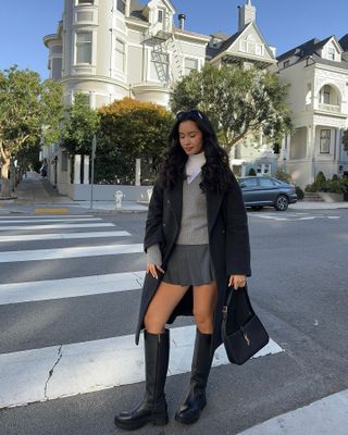 Influencer wears a skirt and knee boots.