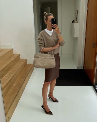 An influencer wears a tan sweater with a brown pencil skirt.