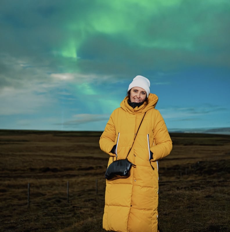 woman wears Orolay Thickened Long Down Jacket in Iceland while watching Northern Lights