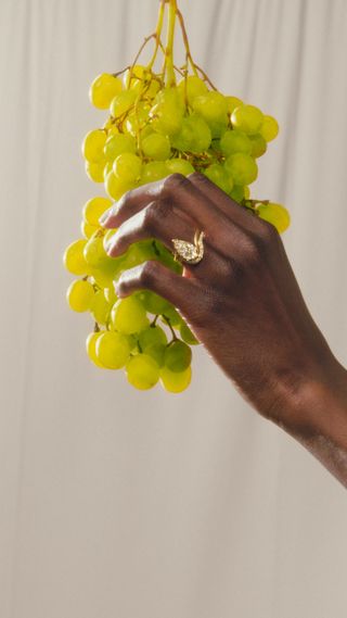 Hand wearing pear-shaped champagne-colored diamond ring and matching band from Aaryah.