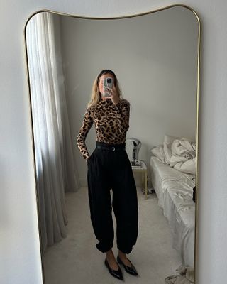 Influencer wearing a leopard-print top, black pants, and pointed-toe flats