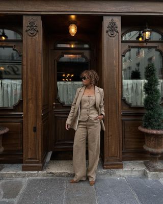 Woman in beige tweed blazer and pants.