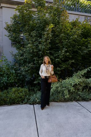 Sandy Koszarek wearing a white long-sleeve, patterned scarf, and dark-wash jeans.