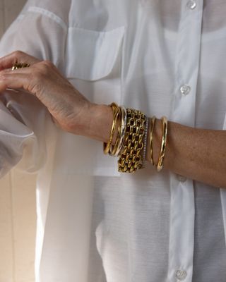 Woman wearing chunky gold bracelets on wrist.