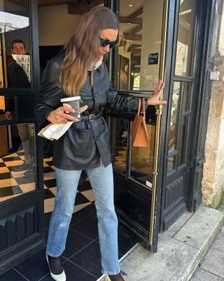  @annelauremais grabbing coffee wearing a leather belted blazer with jeans and ballet flats.