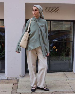 Woman wears sage scarf blouse and tapered trousers