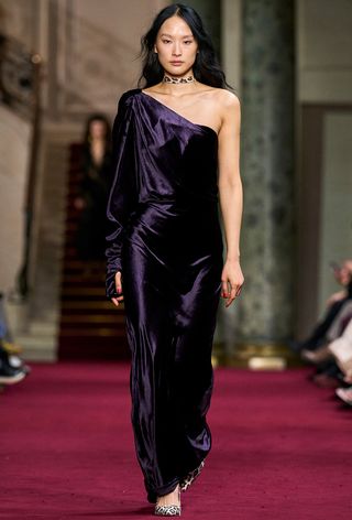 Model walking the Zimmermann fall runway show wearing an asymmetrical purple silk gown with animal print pumps.