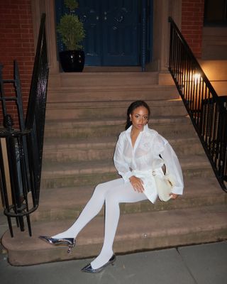 Sierra wears white sheer tights, silver pumps, and a white sheer blouse.