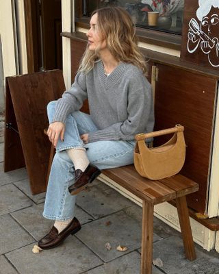 Woman wears grey knit and blue jeans