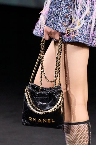 Model on a runway holding the Chanel 22 mini bag.